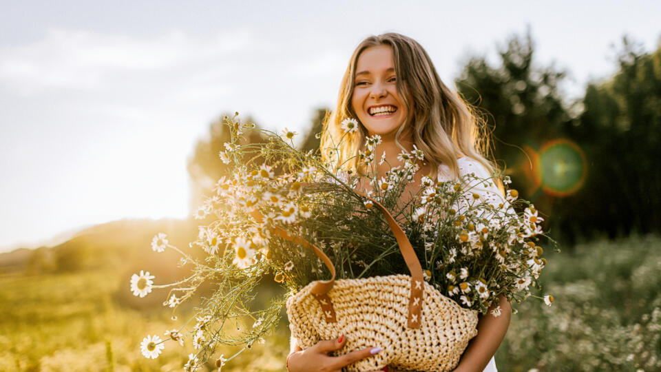 Young adult woman outdoors in camomile field enjoying summer