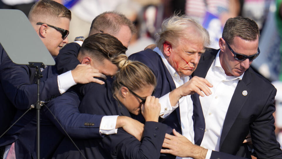 JB 10 Butler - Republikánsky prezidentský kandidát Donald Trump (druhý sprava) odchádza za pomoci ochrankárov z predvolebného mítingu v meste Butler v americkom štáte Pensylvánia 13. júla 2024. Trump potvrdil, že v sobotu na mítingu v Pensylvánii ho zasiahla guľka. Tá mu prestrelila hornú časť pravého ucha. Bývalý americký prezident sa vyjadril na sociálnej sieti, informuje TASR. Bývalého prezidenta Donalda Trumpa evakuovali z pódia na sobotňajšom mítingu po tom, ako sa na podujatí v štáte Pensy