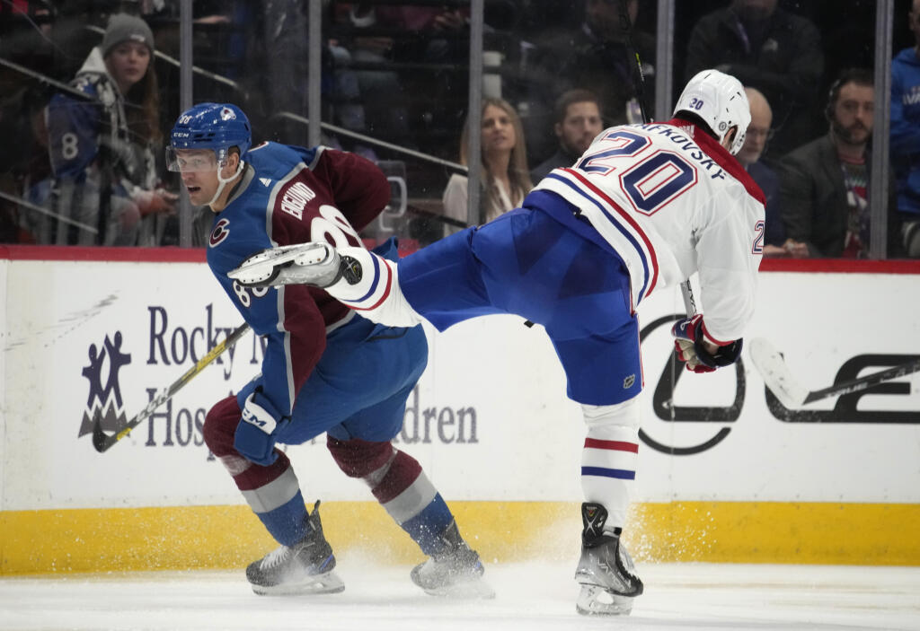 Slovenský hráč Montrealu Canadiens Juraj Slafkovský (vpravo) bojuje o puk s Andreasom Englundom z Colorada Avalanche v zápase hokejovej zámorskej NHL Colorado Avalanche - Montreal Canadiens v Denveri 21. decembra 2022.