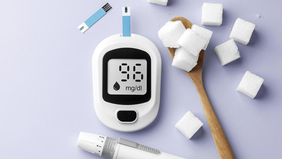 Diabetes concept, blood glucose meter with lancet and sugar cubes in spoon on purple background, top view, copy space