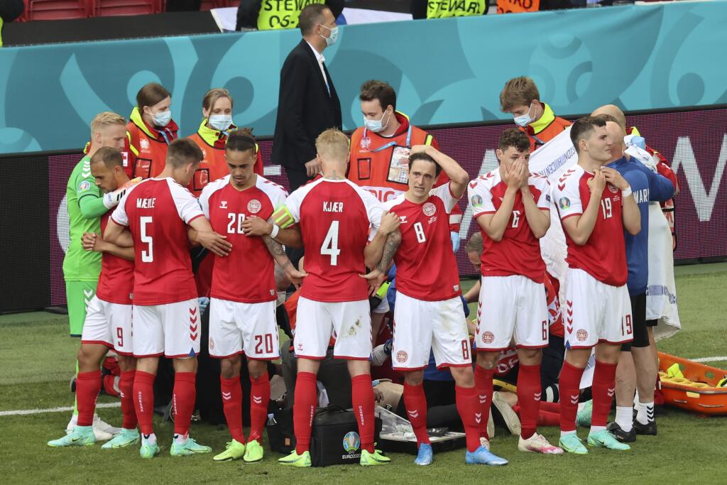 Dánski futbalisti stoja okolo svojho spoluhráča Christiana Eriksena, ktorého záchranári oživujú po tom, čo skolaboval počas zápasu základnej B-skupiny Dánsko - Fínsko na európskom šampionáte v Kodani v sobotu 12. júna 2021.