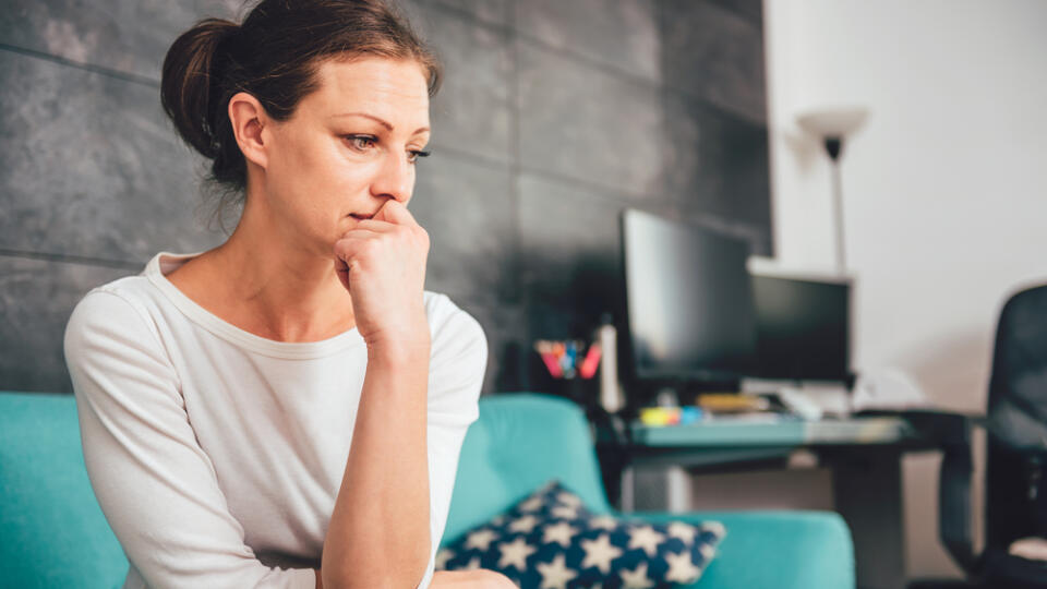 Sad,Woman,Sitting,On,A,Sofa,In,The,Living,Room