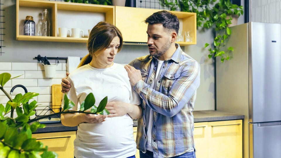 Family conflict. Young family. A pregnant woman and a man quarrel at home, shouting. They stand at home in the kitchen