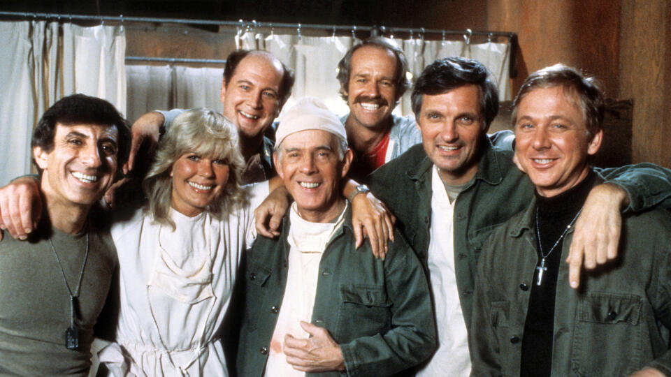 Jamie Farr, Loretta Switová, David Ogden Stiers, Harry Morgan, Mike Farrell, Alan Alda a William Christopher na reklamnom plagáte pre seriál M*A*S*H, asi z roku 1978.