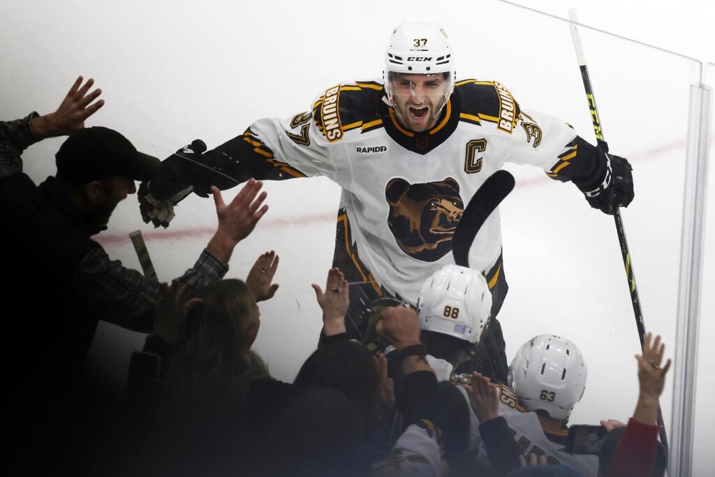 Kapitán Bostonu Bruins Patrice Bergeron sa teší z gólu, ktorý strelil jeho spoluhráč David Pastrňák predĺžení zápasu zámorskej hokejovej NHL Boston Bruins - Carolina Hurricanes v Bostone v piatok 25. novembra 2022.
