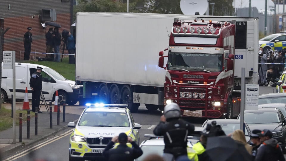 Na snímke policajné autá eskortujú nákladné auto, v ktorom našli 39 mŕtvych osôb v priemyselnom parku 23. októbra 2019 v britskom grófstve Essex.