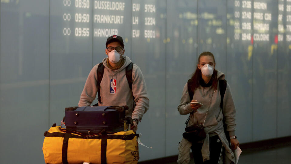 Ľudia s ochrannými rúškami na letisku Schwechat