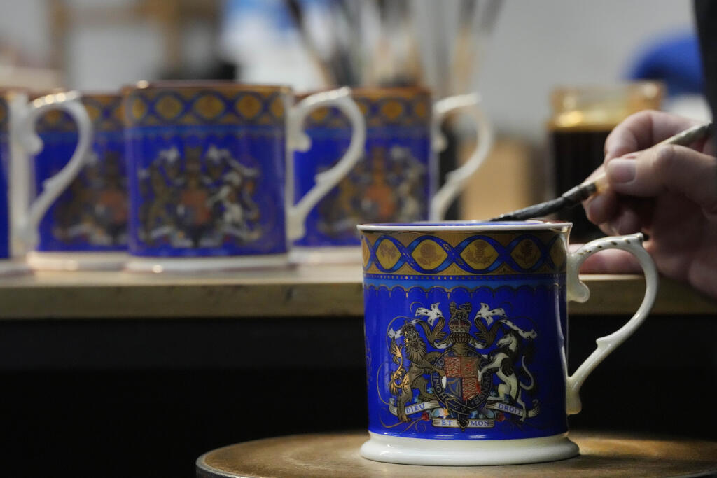 Pracovníčka maľuje porcelánové hrnčeky vo výrobni 13. apríla 2023 v v Stoke-on-Trent. V piatok 14. apríla sa začal  predávať sortiment oficiálneho porcelánu na blížiacu sa korunováciu britského kráľa Karola III., ktorá sa bude konať 6. mája vo Westminsterskom opátstve.