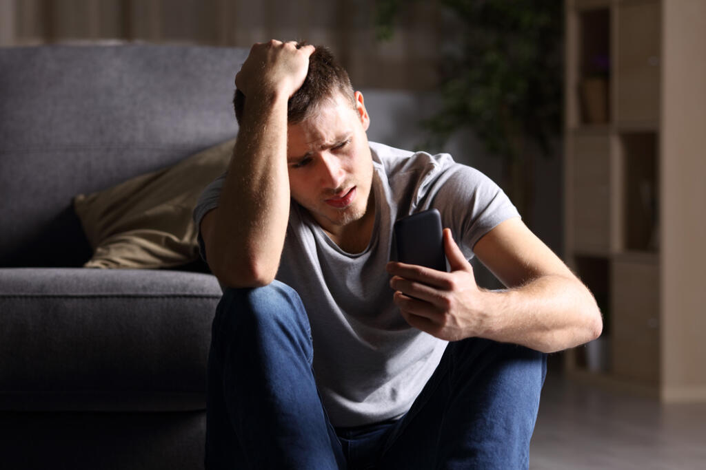 Single,Sad,Man,Checking,Mobile,Phone,Sitting,On,The,Floor