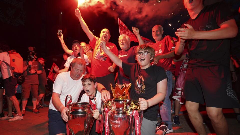 EBE 9 Liverpool - Futbalisti FC Liverpool sú po tridsiatich rokoch opäť anglickými majstrami. Definitívne o tom rozhodla štvrtková prehra Manchestru City na ihrisku londýnskej Chelsea 1:2 v 31. kole Premier League. Liverpool má sedem kôl pred koncom súťaže na čele tabuľky nedostihnuteľný náskok 23 bodov. Na snímke fanúšikovia Liverpoolu oslavujú s replikami pohárových trofejí anglickej Premier League a Ligy majstrov pred štadiónom Anfield v Liverpoole 25. júna 2020. FOTO TASR/AP
Liverpool suppor