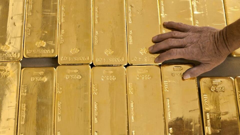 FILE - In this Aug. 8, 2011 file photo a person touches gold bars in the gold store of the Cantonal Bank of Zurich ZKB in Zurich, Switzerland. In Switzerland, a campaign is on to protect the country’s wealth by investing in gold _ a lot of gold. In a test of their sense of financial security, the Swiss are being asked to vote on a proposal to make the central bank hold a fifth of its reserves in gold within five years. That would mean buying 1,500 metric tons, or 1,650 short tons, of gold worth