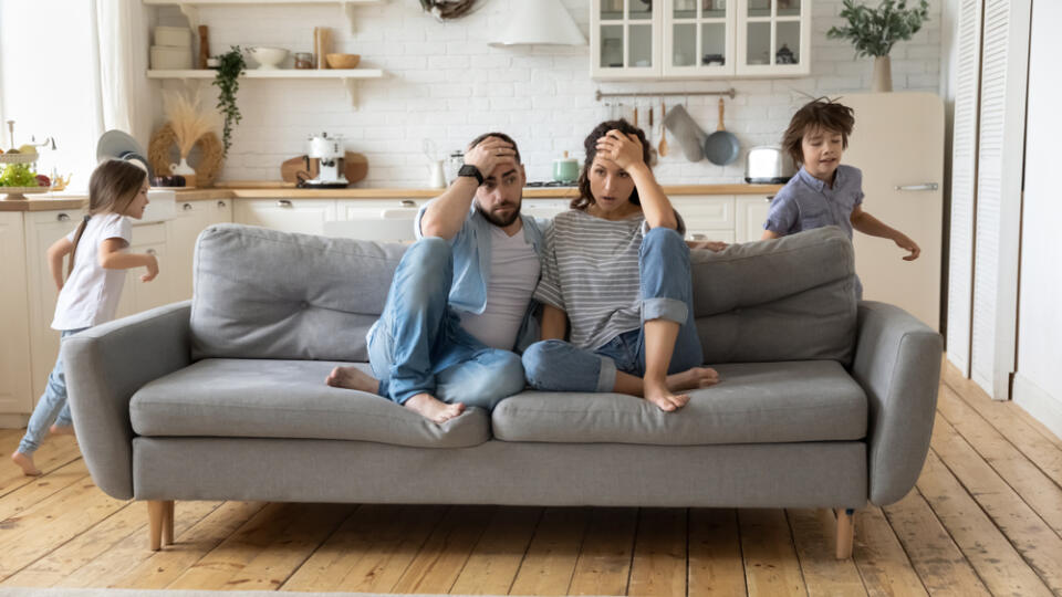 Tired,Mother,And,Father,Sitting,On,Couch,Feels,Annoyed,Exhausted