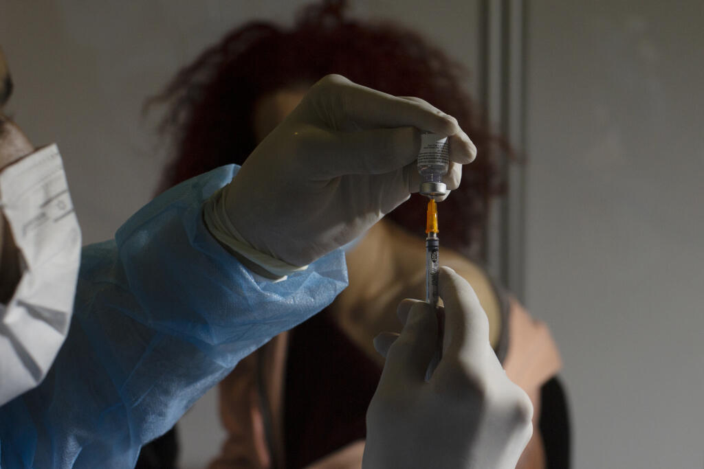 KK32 Jeruzalem - Zdravotník naťahuje do injekčnej striekačky vakcínu proti ochoreniu Covid-19 od spoločnosti Pfizer vo vakcinačnom centre 14. januára 2021 v Jeruzaleme. FOTO TASR/AP
A medical professional prepares to administer the Pfizer COVID-19 vaccine to a woman at a makeshift vaccination center in a sports arena in Jerusalem, Thursday, Jan. 14, 2021. (AP Photo/Maya Alleruzzo)