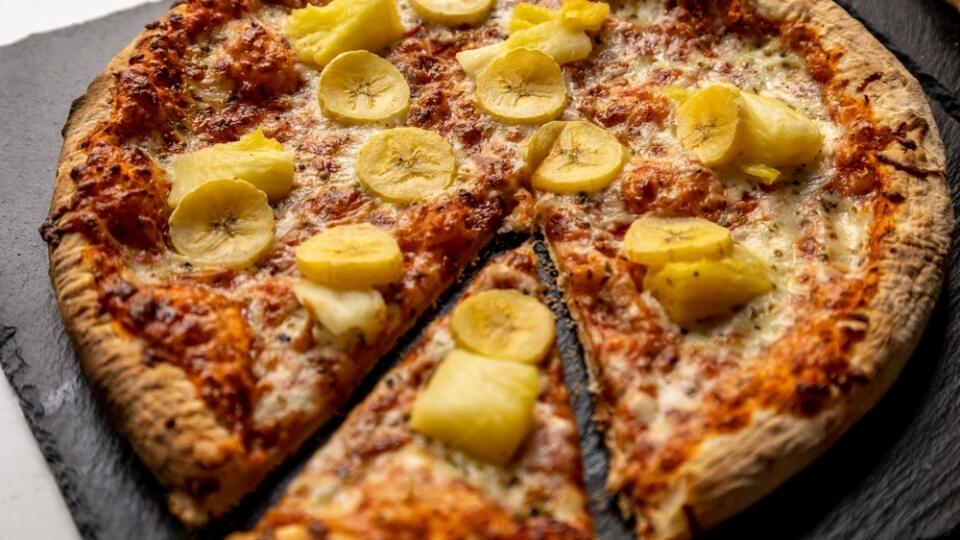 A closeup shot of a round pizza topped with bananas and pineapples