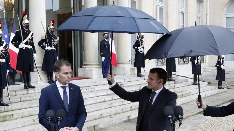 Francúzsky prezident Emmanuel Macron (vpravo) drží dáždnik nad slovenským premiérom Igorom Matovičom počas vyhlásenia pred spoločným rokovaním 3. februára 2021 v Elyzejskom paláci v Paríži.