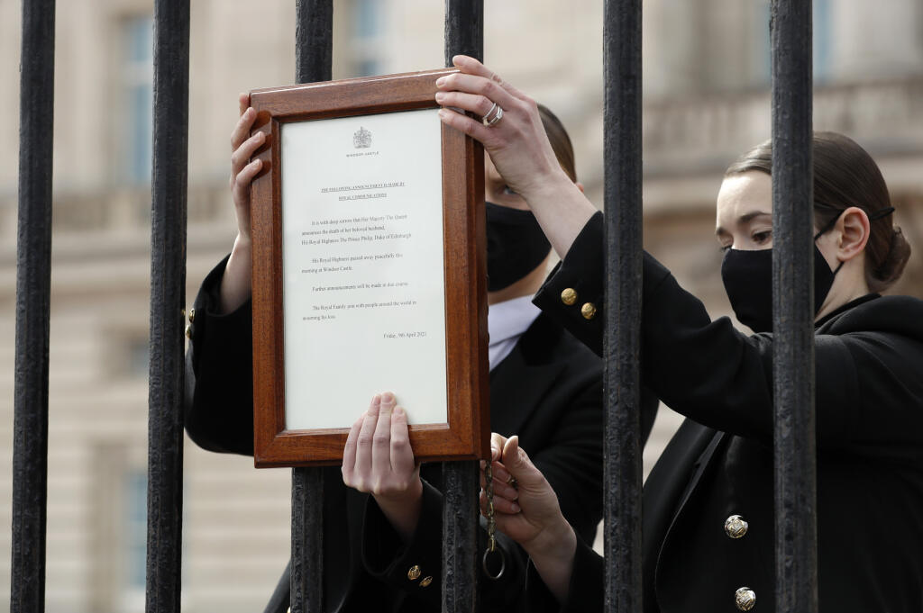 Členovia personálu vešajú oznámenie o úmrtí britského princa Philipa na bránu Buckinghamského paláca 9. apríla 2021 v Londýne. Britský princ Philip, manžel kráľovnej Alžbety II., zomrel v piatok vo veku 99 rokov. Oznámil to Buckinghamský palác.