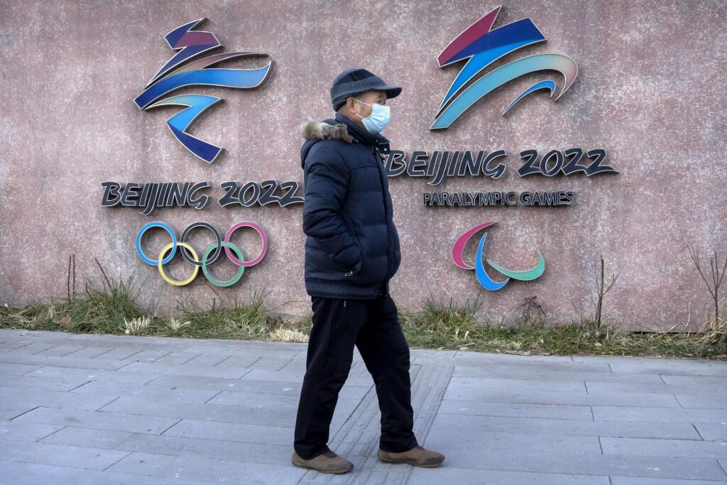 WA 38 Peking - Muž s ochranným rúškom na tvári kráča okolo loga zimných olympijských a paralampijských hier pred sídlom organizačného výboru hier v Pekingu vo štvrtok 16. decembra 2021.  FOTO TASR/AP