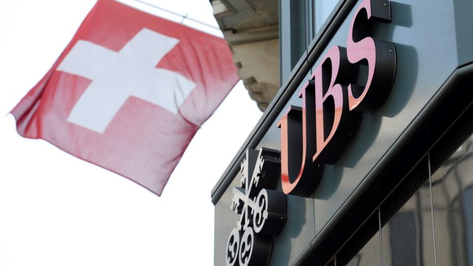 Na archívnej snímke z 24. apríla 2014 švajčiarska vlajka veje nad logom banky UBS v Zürichu. Švajčiarskej banke UBS sa darí. Po dobrom začiatku roka dokázala výrazne zvýšiť zisk aj v 2. kvartáli. Vďačí za to dobrým výsledkom v oblasti správy majetku. FOTO TASR/AP