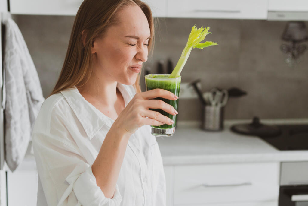 Young,Woman,Drinking,Healthy,Spinach,And,Celery,Smoothie,At,Home