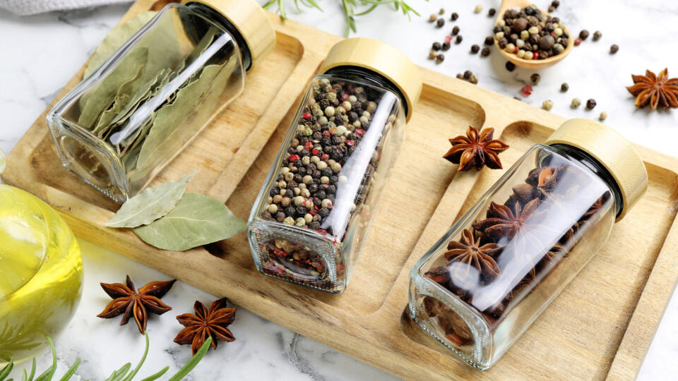 Glass jars with different spices on white marble table