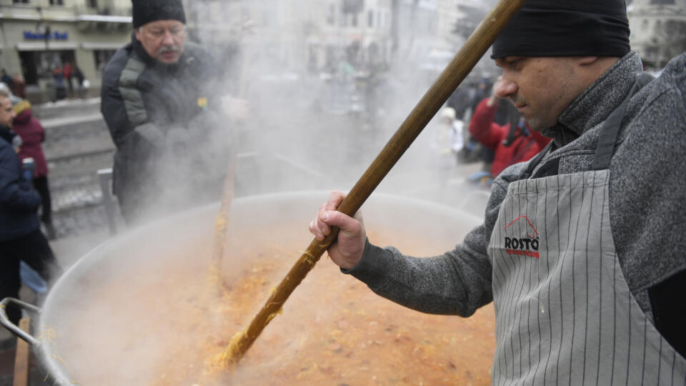 Na snímke muži miešajú kapustnicu, ktorú varia v 1000-litrovom kotli počas charitatívneho projektu s názvom Anjelská kapustnica na Hlavnej ulici v Košiciach 17. decembra 2022. Výťažok z podujatia sa venuje organizácii Úsmev ako dar, ktorá pomáha rodinám v núdzi. FOTO TASR – František Iván