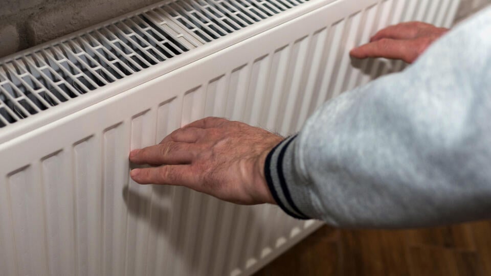 An,Elderly,Man,Warms,His,Hands,Near,A,Heating,Radiator,