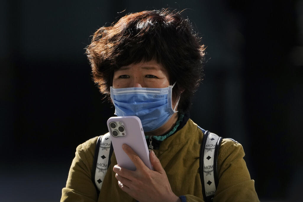 KK14 Peking - Žena s ochranným rúškom používa iPhone 7. novembra 2022 v Pekingu. Čína v pondelok hlásila najvyšší počet nakazených za posledných šesť mesiacov. Stalo sa tak napriek tomu, že komunistická vláda v Pekingu nepoľavuje v uplatňovaní čoraz nepopulárnejšej stratégie nulovej tolerancie covidu, spojenej so zavádzaním striktných lockdownov.  Americká spoločnosť Apple v nedeľu večer oznámila, že jej továreň v Čeng-čou funguje len vo výrazne obmedzenom režime. Upozornila preto svojich zákazn