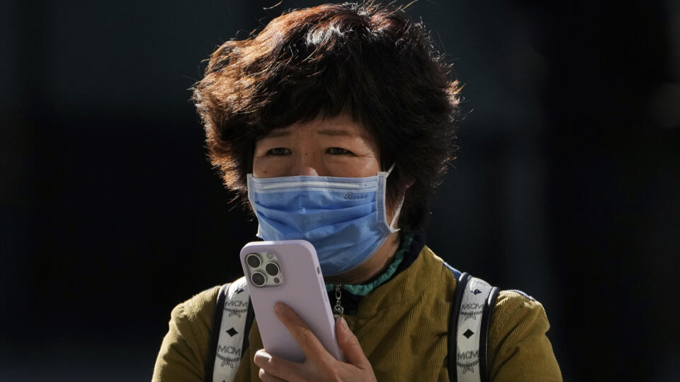 Žena s ochranným rúškom používa iPhone 7. novembra 2022 v Pekingu. Čína v pondelok hlásila najvyšší počet nakazených za posledných šesť mesiacov. Stalo sa tak napriek tomu, že komunistická vláda v Pekingu nepoľavuje v uplatňovaní čoraz nepopulárnejšej stratégie nulovej tolerancie covidu, spojenej so zavádzaním striktných lockdownov. Americká spoločnosť Apple v nedeľu večer oznámila, že jej továreň v Čeng-čou funguje len vo výrazne obmedzenom režime. Upozornila preto svojich zákazn