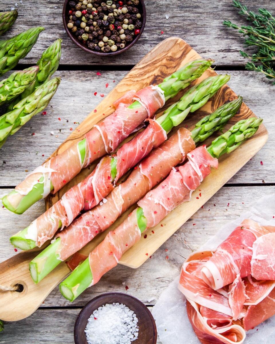 Fresh,Organic,Asparagus,Wrapped,In,Parma,Ham,On,A,Cutting