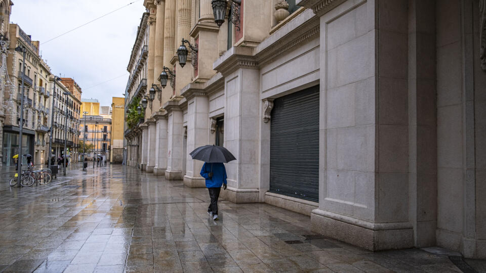 A woman an umbrella seen walking past the closed stores