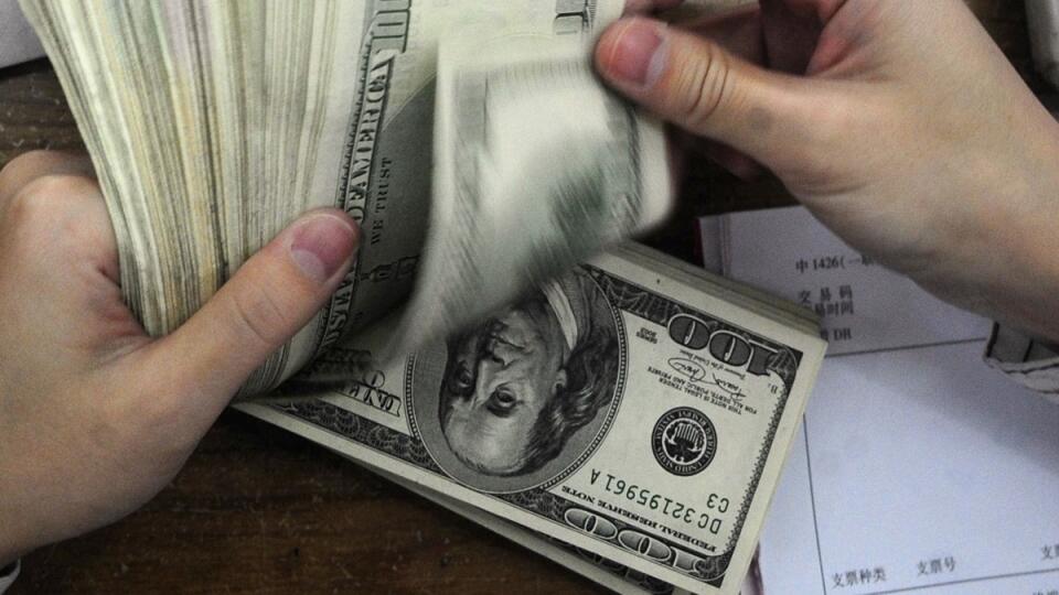FILE - In this Oct. 16, 2009 file photo, a bank clerk counts U.S. dollar notes near bundles of Chinese renminbi notes at a bank in Hefei in central China's Anhui province. China retained its spot as the biggest foreign holder of U.S. Treasury debt in January of 2010 although it trimmed its holdings for a third straight month. The string of declines are likely to underscore worries that the U.S. government could face much higher interest rates to finance soaring budget deficits. (AP File Photo) *