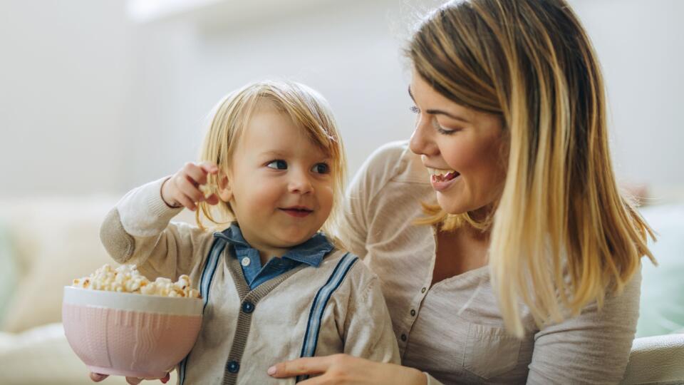 Smiling little boy and his mother eating popcorn.