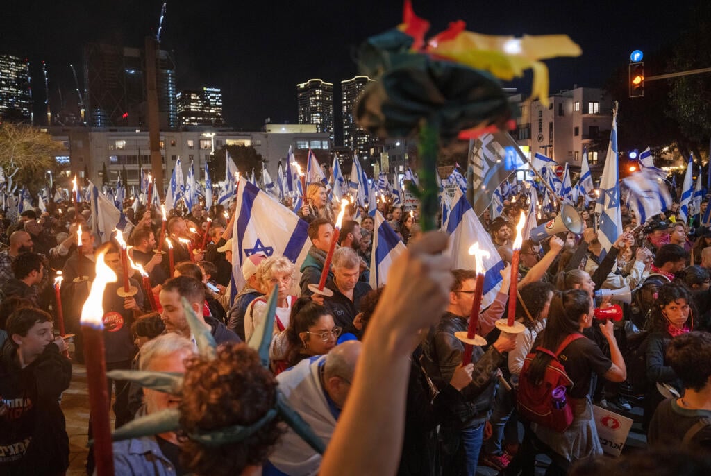 Izraelskí demonštranti držia pochodne počas protestu proti vládnemu návrhu súdnej reformy