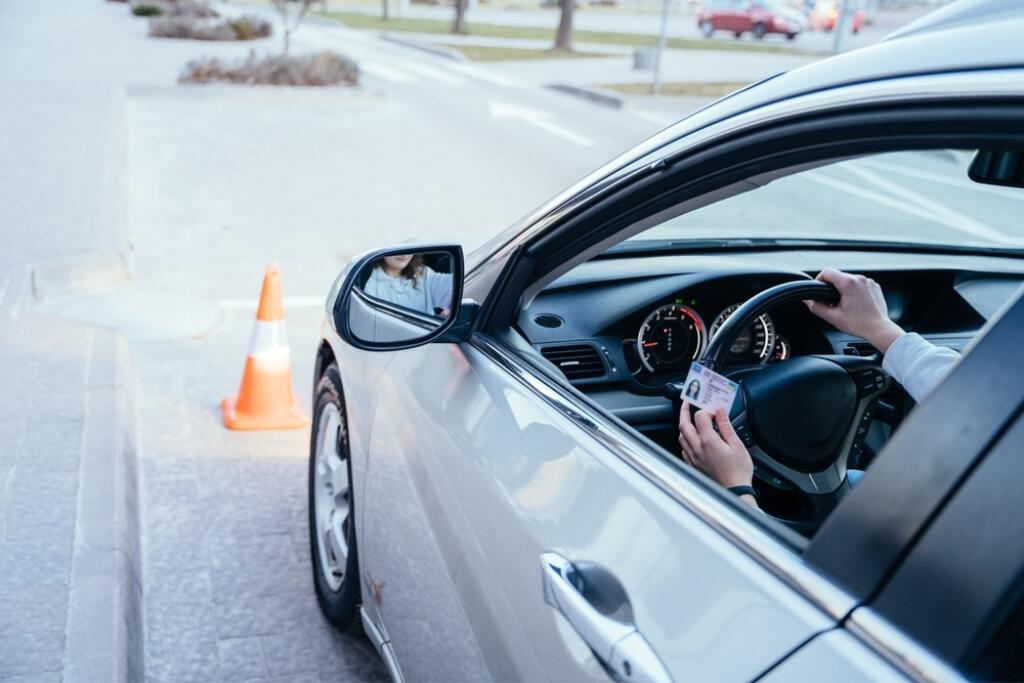 Close,Up,Of,Womand,Hands,On,Wheel,With,Driving,License.
