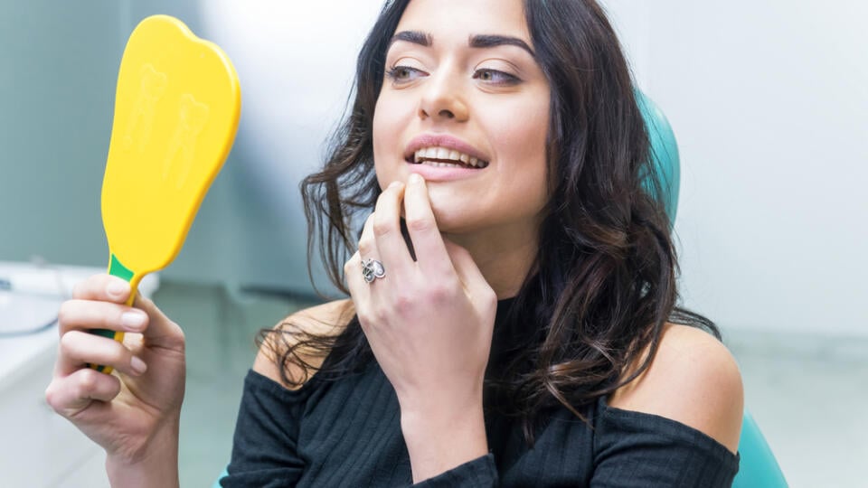 Woman,Checking,Teeth,In,Mirror.,Female,At,The,Dentist,Office.