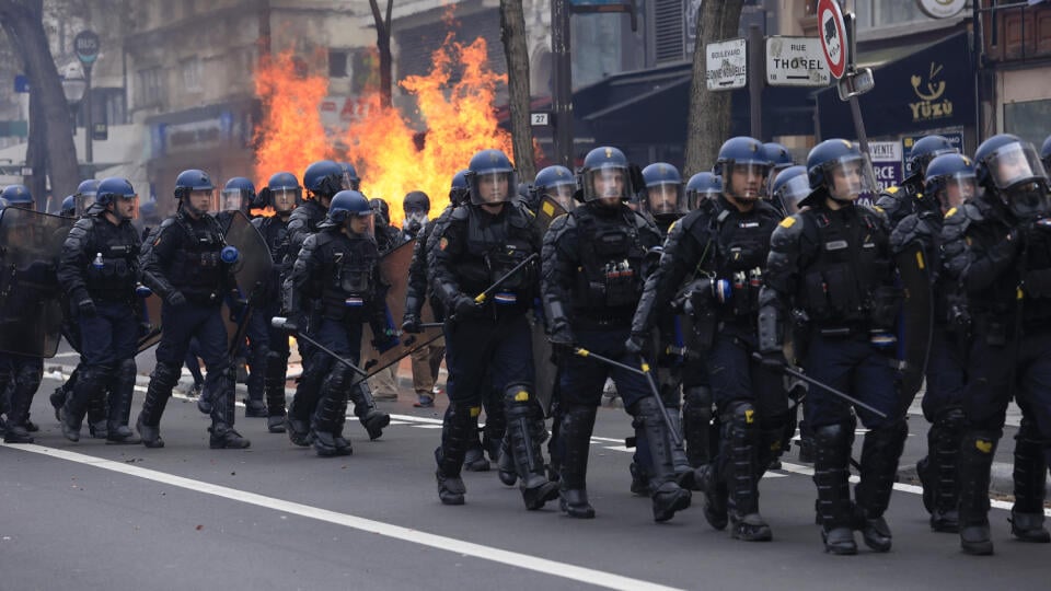 Poriadková polícia sa presúva okolo horiacich odpadkov pozásahu počas pokračujúcich protestov proti nepopulárnej dôchodkovej reforme, ktorú presadil prezident Emmanuel Macron v Paríži vo štvrtok 23. marca 2023.