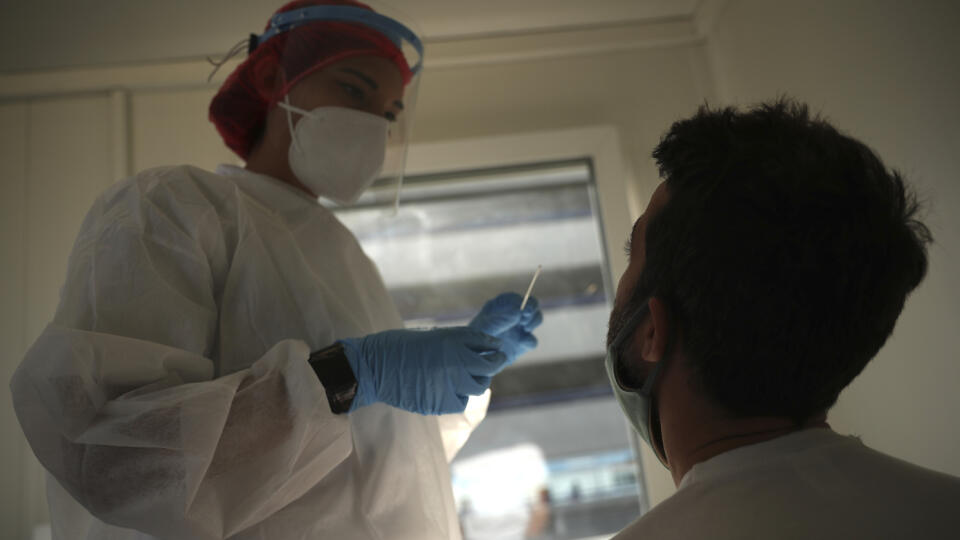 Belgická zdravotníčka v ochrannom odeve a s ochranným štítom na zabránenie šíreniu nového koronavírusu hovorí s pasažierom, ktorý práve pristál lietadlom v Belgicku počas testovania na ochorenie COVID-19 na medzinárodnom letisku Zaventem v Bruseli 17. septembra 2020.