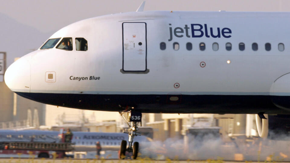 A police officer watches as a JetBlue aircraft, with its front landing gear turned sideways and smoking, makes an emergency landing at Los Angeles International Airport in this September 21, 2005 file photo. Suspense in the skies from airliners with problems is fast becoming a staple of cable news television in the U.S., aided by satellite-equipped news crews from local affiliates that allow the images to be shown live. On December 21, 2005, it was a Learjet circling above Spirit of St. Louis Ai