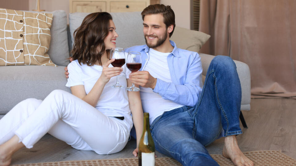 Happy,Couple,Sitting,,Relaxing,On,Floor,In,Living,Room,,Drinking