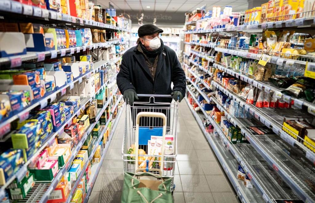17 March 2020, Berlin: A customer wearing a face mask and gloves goes shopping in the early morning in a supermarket in the Berlin district of Friedenau. In order to slow down the spread of the coronavirus, the German government has considerably restricted public life. Photo: Kay Nietfeld/dpa (Photo by Kay Nietfeld/picture alliance via Getty Images)