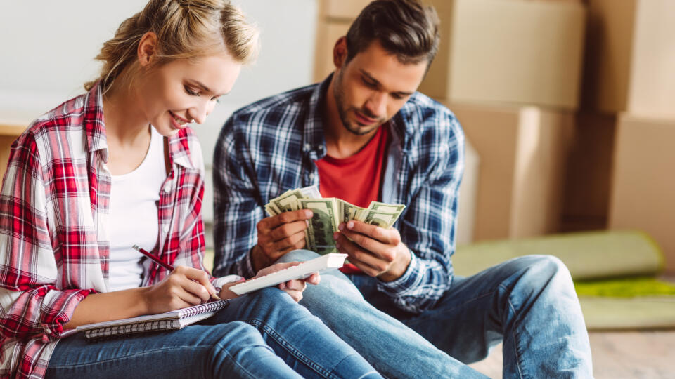Young,Couple,Counting,Money,While,Sitting,On,Floor,In,New