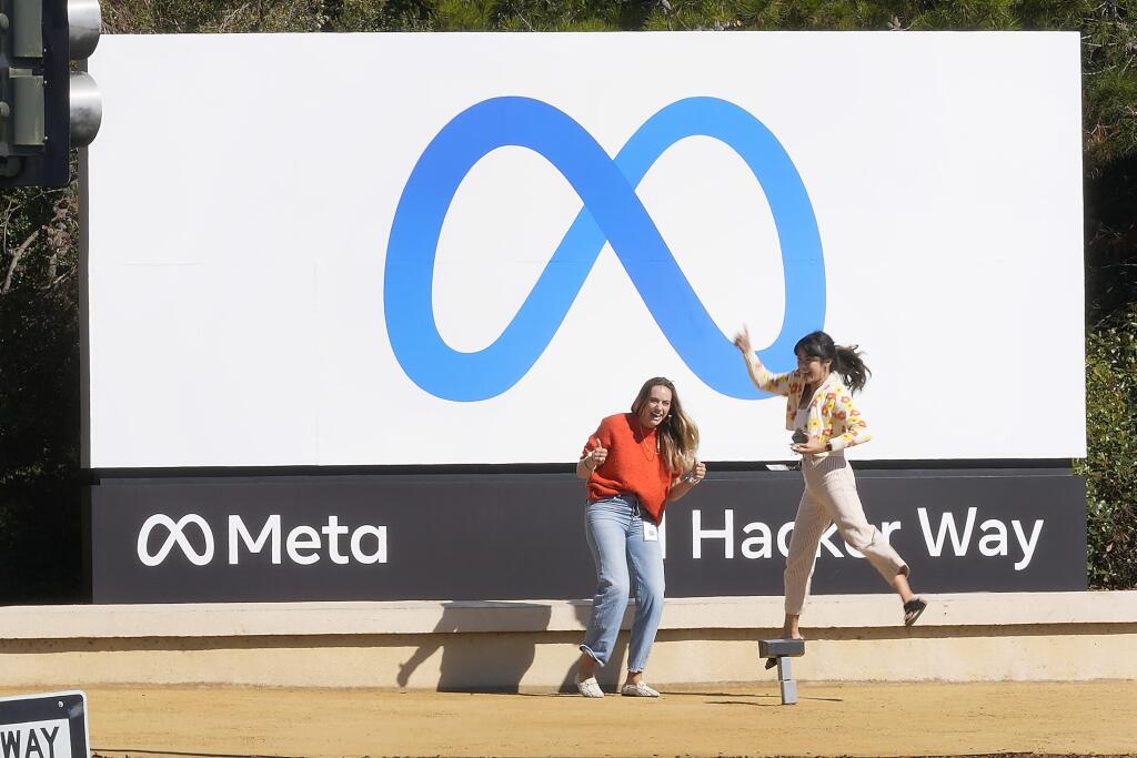 KK6 Menlo Park - Spoločnosť Facebook odhalila nové logo a nový názov Meta v sídle spoločnosti 28. októbra 2021 v Menlo Parku. Generálny riaditeľ americkej spoločnosti Facebook Mark Zuckerberg vo štvrtok oznámil, že jeho firma sa premenuje na Meta. Ide o súčasť jeho snahy obsiahnuť v názve spoločnosti svoju víziu virtuálnej reality pre budúcnosť, ktorú Zuckerberg nazýva metaverzum. FOTO TASR/AP 
Facebook employees take a photo with the company's new name and logo outside its headquarters in Menlo