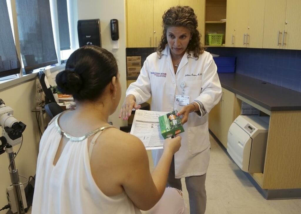 Dr. Juliana Duque, right, gives a patient, who is in her first trimester of pregnancy insecticide and and information about mosquito protection at the Borinquen Medical Center, Tuesday, Aug. 2, 2016 in Miami. The CDC has advised pregnant women to avoid travel to the nearby neighborhood of Wynwood where mosquitoes are apparently transmitting Zika directly to humans. The patient also had a test for the Zika virus following her exam. (AP Photo/Lynne Sladky)