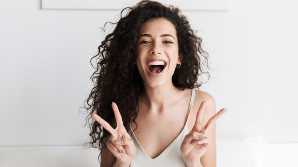 Happy,Young,Girl,With,Dark,Curly,Hair,Sitting,In,Bed