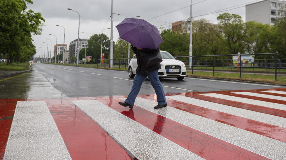Na snímke žena s dáždnikom kráča cez priechod pre chodcov počas dažďa v bratislavskej mestskej časti Ružinov 17. mája 2021. FOTO TASR - Jaroslav Novák