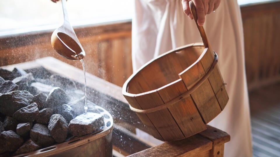 Man,Pouring,Water,Onto,Hot,Stone,In,Sauna,Room.,Steam