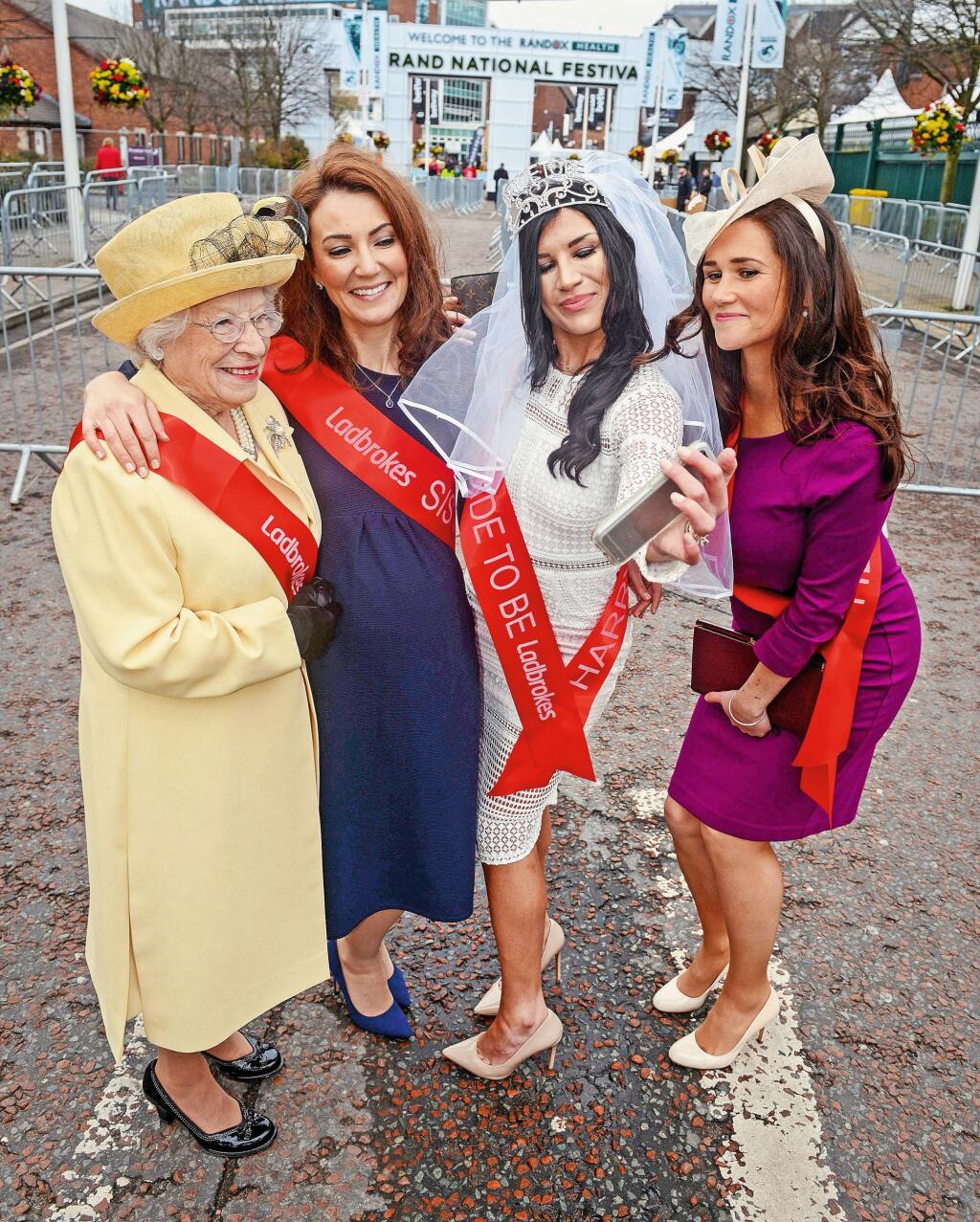 Lookalike members of the Royal family including Meghan Markle, The Queen, Kate Middleton and Pippa Middleton arrive at Aintree Racecourse after putting bets on their horses at Ladbrokes. 12 April 2018. See SWNS story. Racegoers at Aintree were stunned today when they saw Meghan Markle celebrating her hen party with The Queen and The Duchess of Cambridge at the Grand National Festival. The bride-to-be and her future grandmother and sister-in-law were spotted at the home of the Grand National enj