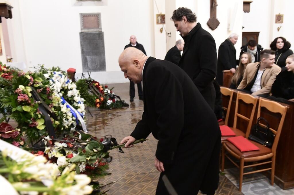 Smútoční hostia hádzali k truhle kvety a vence.