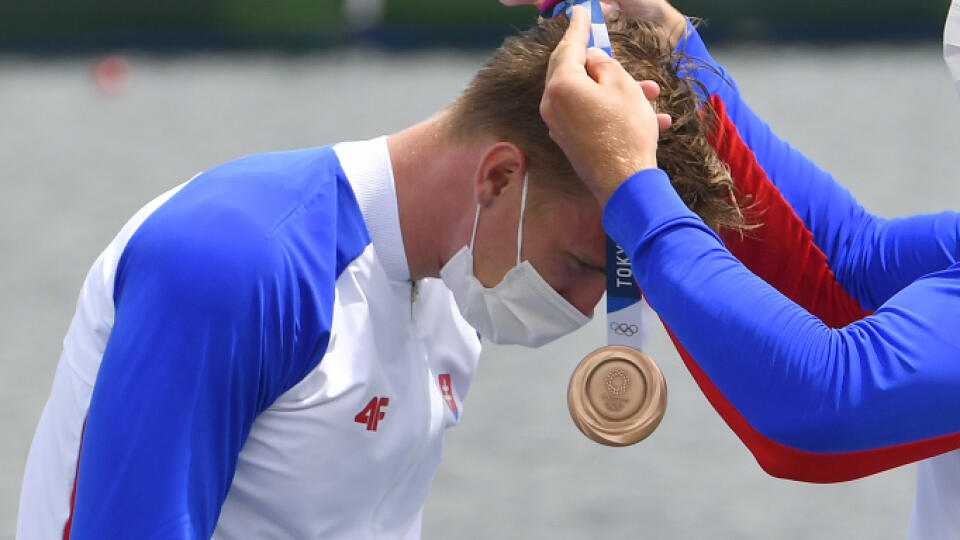 Na snímke slovenská posádka rýchlostných kanoistov K4 v zložení Samuel Baláž, Denis Myšák, Erik Vlček a Adam Botek získala bronzovú medailu na 500 metrov počas XXXII. letných olympijských hier v Tokiu, 7. augusta 2021. Na snímke Denis Myšák dekoruje Samuela Baláža bronzovou medailou, ktorú im priniesla Danka Barteková (vľavo) počas medailového ceremoniálu. FOTO TASR - Michal Svítok