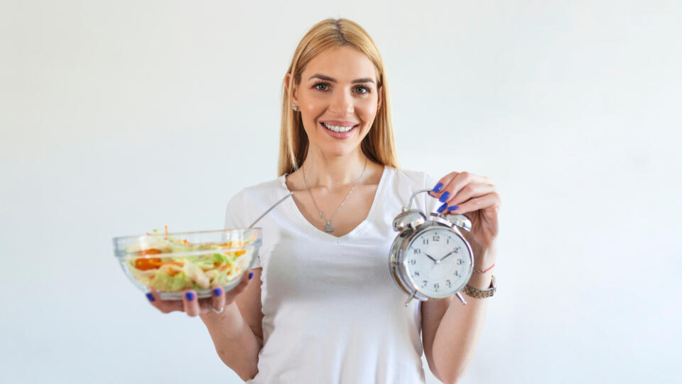 Young,Woman,Holding,Clock,And,Healthy,Food,Of,Salad,Intermittent